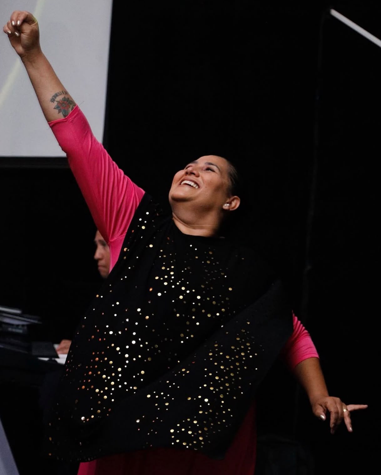Mulher adorando com os braços erguidos durante o culto