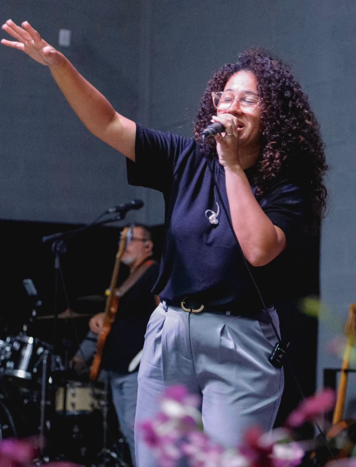 Cantora de cabelos cacheados conduzindo o louvor